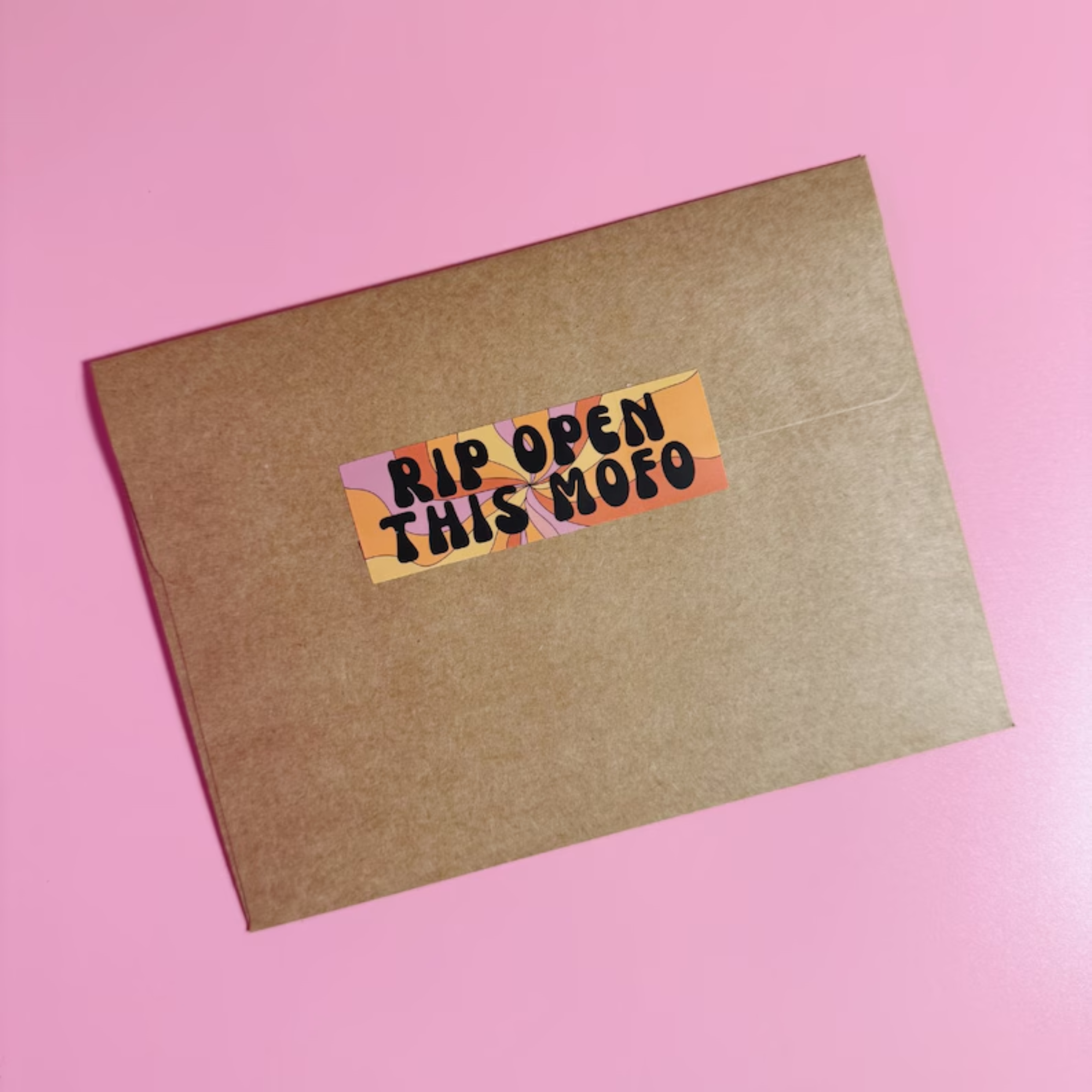 Kraft paper envelope with a colorful sticker on a pink background